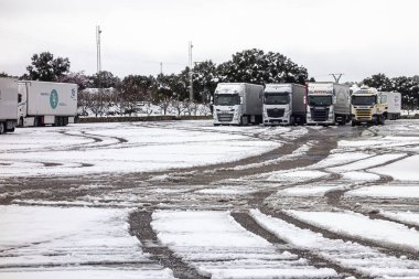 Guadalajara, İspanya; 03-16-2025: İspanya 'da karla kaplı A2 karayolu (Autovia del Nordeste) boyunca giden kamyon, kışın manzarası ve bulutlu gökyüzü ile çevrilidir. Soğuk hava lojistiği hareket halinde