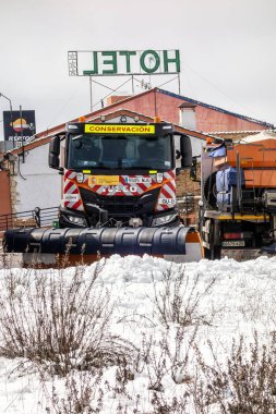 Guadalajara, İspanya; 03-16-2025: Bir otelin ve benzin istasyonunun bulunduğu karayolu bakım kar temizleme aracının ön görüntüsü.