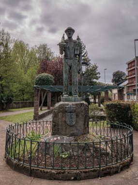 Torre del Bierzo, Leon, İspanya; 04-17-2025: Gömlek kollarıyla bir madenciyi onurlandıran bronz heykel, bir çekiç, bir karbit lamba ve şehrin arması üzerindeki bir parkta bulunan bir balta