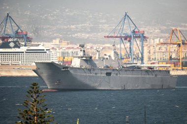 Malaga, İspanya; 07 / 08 / 2025: İspanyol uçak gemisi Juan Carlos I ile askeri helikopter ve yolcu gemisi Mlaga limanında. Şehir silüeti ve deniz manzarası Bu deniz ve sivil deniz manzarası