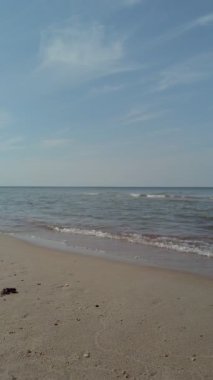 Baltık kıyılarının huzurlu deniz manzarası sakin gök mavisi dalgaları açık mavi gökyüzünün altında boş kumlu sahillerde süzülüyor. Hiçbir insan dikey deniz manzarası olmadan doğal arka plan.