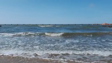 Baltık kıyılarının sakin deniz manzarası açık mavi gökyüzünün altında açık mavi bir yaz gününde masmavi dalgalar dalgaları dalgalandırıyor. Hiçbir insan doğal arka planı terk etmez..