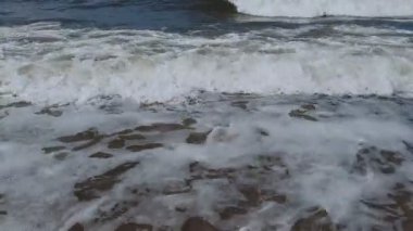 Baltık sahilinin boş kumlu sahillerinde, parlak bir yaz gününde, fırtınalı deniz dalgaları yaklaşıyor. Sakin deniz manzarası, soyut su yüzeyi doğal arka plan..