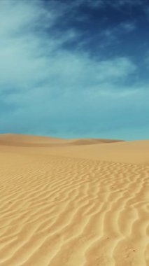 Gündüz vakti bulutlu mavi gökyüzünün altında devasa kum tepeleri olan boş kumlu çölde hareket. Hiçbir insan vahşi doğa manzarası minimalist konsept 3D animasyon.