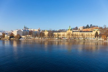 Çek Cumhuriyeti 'nin güneşli bir günde Vltava Nehri üzerindeki Prag Kalesi ile Karlı Prag Küçük Kasabası