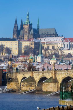 Çek Cumhuriyeti 'nin güneşli bir günde Vltava Nehri üzerindeki Prag Kalesi ile Karlı Prag Küçük Kasabası