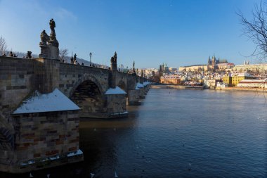 Çek Cumhuriyeti 'nin güneşli bir günde Vltava Nehri üzerindeki Prag Kalesi ile Karlı Prag Küçük Kasabası