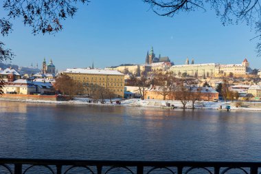 Çek Cumhuriyeti 'nin güneşli bir günde Vltava Nehri üzerindeki Prag Kalesi ile Karlı Prag Küçük Kasabası