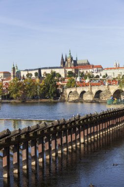 Çek Cumhuriyeti 'nin güneşli bir gününde Vltava Nehri üzerindeki Gotik Kalesi ve Charles Köprüsü ile Sonbahar Renkli Prag Küçük Kasabası