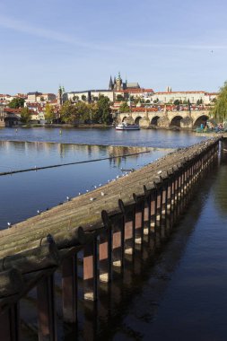 Çek Cumhuriyeti 'nin güneşli bir gününde Vltava Nehri üzerindeki Gotik Kalesi ve Charles Köprüsü ile Sonbahar Renkli Prag Küçük Kasabası