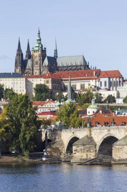 Çek Cumhuriyeti 'nin güneşli bir gününde Vltava Nehri üzerindeki Gotik Kalesi ve Charles Köprüsü ile Sonbahar Renkli Prag Küçük Kasabası