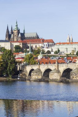 Çek Cumhuriyeti 'nin güneşli bir gününde Vltava Nehri üzerindeki Gotik Kalesi ve Charles Köprüsü ile Sonbahar Renkli Prag Küçük Kasabası