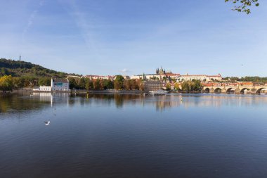 Çek Cumhuriyeti 'nin güneşli bir gününde Vltava Nehri üzerindeki Gotik Kalesi ve Charles Köprüsü ile Sonbahar Renkli Prag Küçük Kasabası
