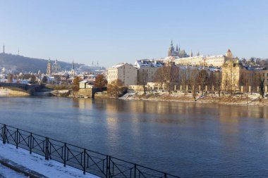 Çek Cumhuriyeti 'nin güneşli bir günde Vltava Nehri üzerindeki Prag Kalesi ile Karlı Prag Küçük Kasabası