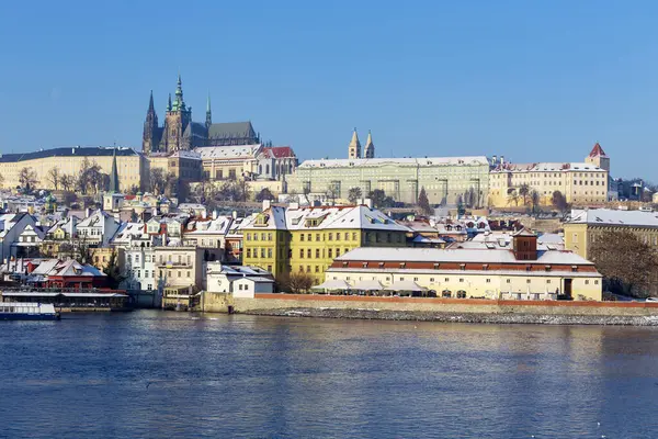 Çek Cumhuriyeti 'nin güneşli bir günde Vltava Nehri üzerindeki Prag Kalesi ile Karlı Prag Küçük Kasabası