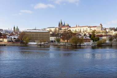 Çek Cumhuriyeti 'nin güneşli bir günde Vltava Nehri üzerindeki Prag Kalesi ile Karlı Prag Küçük Kasabası