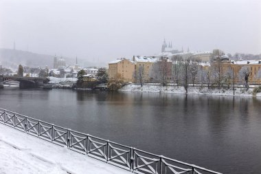 Kar gibi sisli Prag Küçük Kasabası Vltava Nehri üzerindeki gotik kalesiyle, kar yağıyor, Çek Cumhuriyeti