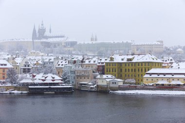 Kar gibi sisli Prag Küçük Kasabası Vltava Nehri üzerindeki gotik kalesiyle, kar yağıyor, Çek Cumhuriyeti
