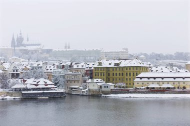 Kar gibi sisli Prag Küçük Kasabası Vltava Nehri üzerindeki gotik kalesiyle, kar yağıyor, Çek Cumhuriyeti