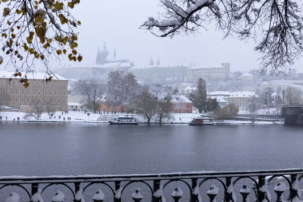 Kar gibi sisli Prag Küçük Kasabası Vltava Nehri üzerindeki gotik kalesiyle, kar yağıyor, Çek Cumhuriyeti