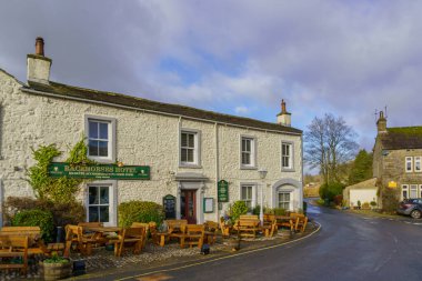 Kettlewell 'deki Racehorses Oteli, Skipton, Yukarı Nidderdale, Kuzey Yorkshire, İngiltere, ana girişe yakın ahşap masalar ve sandalyeler ve beyaz duvarlar ile.