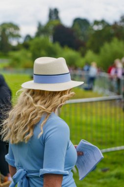 Ripley Show 'da uzun sarı saçlı bir kadın, Kuzey Yorkshire, İngiltere; açık mavi kurdeleli bir Orford fötr şapkası ve ona uyan bir elbise giyiyor..