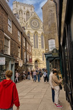 Tourists and sightseers strolling down Stonegate Street, with York Minster ahead in the distance, York, North Yorkshire, UK. clipart