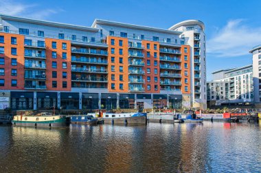 Mavi gökyüzünün altında huzurlu bir şehir kanalı modern deniz manzaralı apartman ve mavna, Leeds, Batı Yorkshire, İngiltere 'ye ev sahipliği yapar..