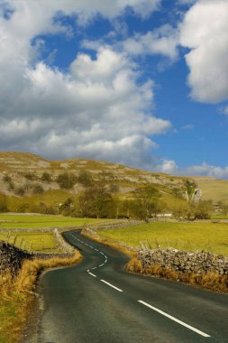 Dolambaçlı bir köy yolu, çarpıcı Yorkshire Dales arazisinde huzurlu bir yolculuğa davet ediyor..