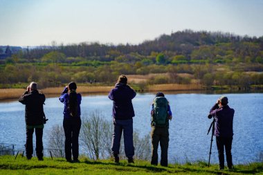 Açık hava meraklıları çimenli bankada kuş gözlemcileri, RSPB St. Aidan 's, Leeds, West Yorkshire, İngiltere.