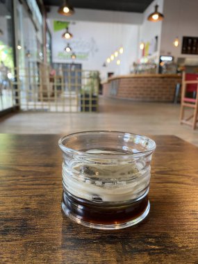 Kahveli bir bardak ve ahşap bir masanın üzerinde buzlu bir bardak parlak ışıklı bir ofis tarzı bar ve rahatlatıcı bir alan.