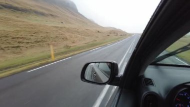 İzlanda 'da bir yolda giden araba manzarayı ve dağları izliyor. Araba penceresinden manzarayı seyrediyor. yatay.