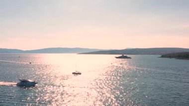 Gün batımında açık denizde yelken açacağız. Yat gün batımında dalgalar üzerinde yelken açar. Sürat teknesi denizde geziyor.