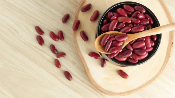 stock image red kidney beans in a black bowl and spoon on wooden background, top view, flat lay, top-down, selective focus.copy space.