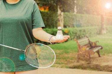 Beyaz kremalı badminton mekikleri ve badminton raketleri hazır, bulanık ağaç arka plan fikirleri parkta sağlıklı bir spor için.