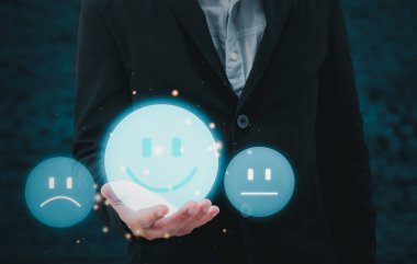 Müşteri hizmetleri ve Memnuniyet kavramından çok etkilenen bir iş adamı, mutlu gülümseme ikonu üzerinde sanal ekranı tutuyor..