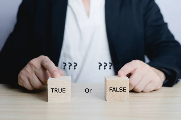businessman is selecting a block that has the word true or false on it. deciding Think with true or false options. Business options for difficult situations true or false and question mark