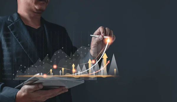 Erkek büyüyen grafikler çizer ve ticaretin ilerlemesini ve mali ve yatırımları analiz eder. Teknolojiyi başarı hedefleri ve büyüyen hisse senetlerine strateji planlamak için kullanın. Çevrimiçi ticaret, ekonomik ve çevrimiçi pazarlama.