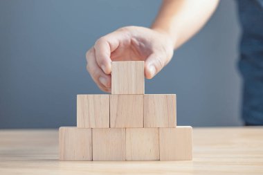 Metin ya da semboller için sekiz blok boş tahta istifleyen bir işadamının eli, büyüme süreci için geliştirme kavramı.