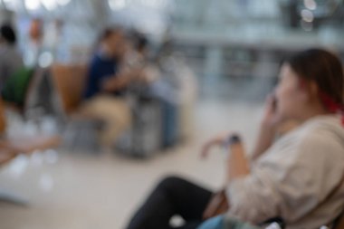 Koridorda cep telefonuyla konuşan bir kadın ve havaalanı terminalindeki bir grup yolcunun bulanık görüntüleri..