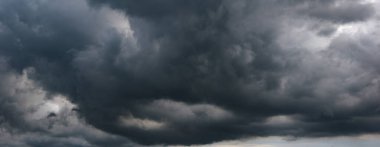 Uğursuz bulutlarla dolu karanlık bir gökyüzü, kötü havanın şiddetini ve değişen iklim koşullarının öngörülemez etkilerini yansıtan bir sahne hazırlar..