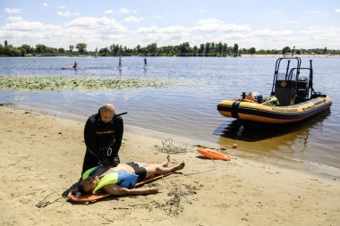 Ukraynalı bir kurtarma görevlisi, Ukrayna 'nın Kyiv plajında, 06 Temmuz 2024' te eğitim gören bir adama ilk yardım sağlıyor. Yüksek kalite fotoğraf