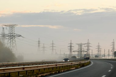 Güneş doğarken, sisli bir sabahta elektrik hatlarının metal destekleri. Yüksek kalite fotoğraf