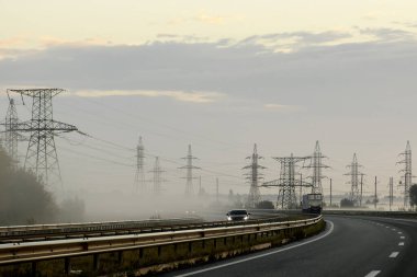 Güneş doğarken, sisli bir sabahta elektrik hatlarının metal destekleri. Yüksek kalite fotoğraf