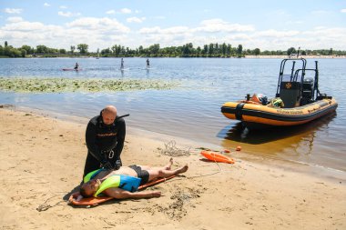 Ukraynalı bir kurtarma görevlisi, Ukrayna 'nın Kyiv plajında, 06 Temmuz 2024' te eğitim gören bir adama ilk yardım sağlıyor. Yüksek kalite fotoğraf