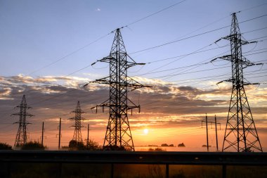 Güneş doğarken, sisli bir sabahta elektrik hatlarının metal destekleri. Yüksek kalite fotoğraf