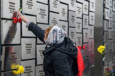 İnsanlar, Rus işgali kurbanlarının anısına 30 Mart 2025 'te, Bucha, Ukrayna' da Rus kuvvetleri tarafından öldürülen sivillerin toplu mezarı yerine çiçek getiriyor. Yüksek kalite fotoğraf