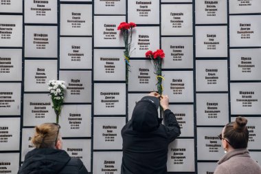 İnsanlar, Rus işgali kurbanlarının anısına 30 Mart 2025 'te, Bucha, Ukrayna' da Rus kuvvetleri tarafından öldürülen sivillerin toplu mezarı yerine çiçek getiriyor. Yüksek kalite fotoğraf