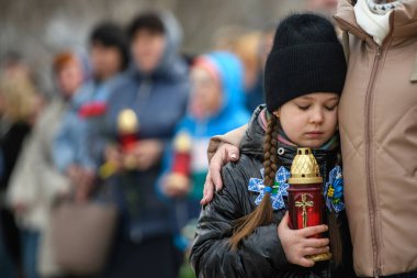 İnsanlar, Rus işgali kurbanlarının anısına 30 Mart 2025 'te, Bucha, Ukrayna' da Rus kuvvetleri tarafından öldürülen sivillerin toplu mezarı yerine çiçek getiriyor. Yüksek kalite fotoğraf