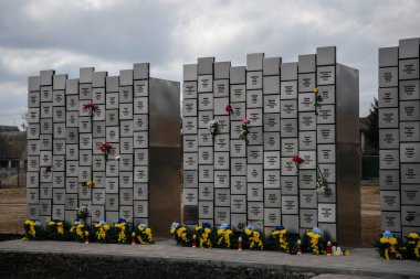 İnsanlar, Rus işgali kurbanlarının anısına 30 Mart 2025 'te, Bucha, Ukrayna' da Rus kuvvetleri tarafından öldürülen sivillerin toplu mezarı yerine çiçek getiriyor. Yüksek kalite fotoğraf
